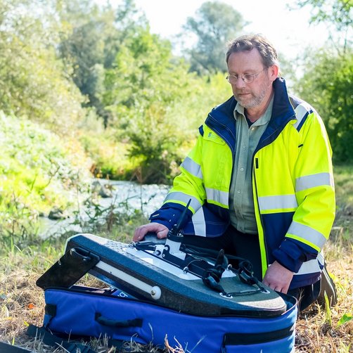 © Bayerisches Staatsministerium für Umwelt und Verbraucherschutz Ein Mann in Sicherheitskleidung und einem Rucksack.