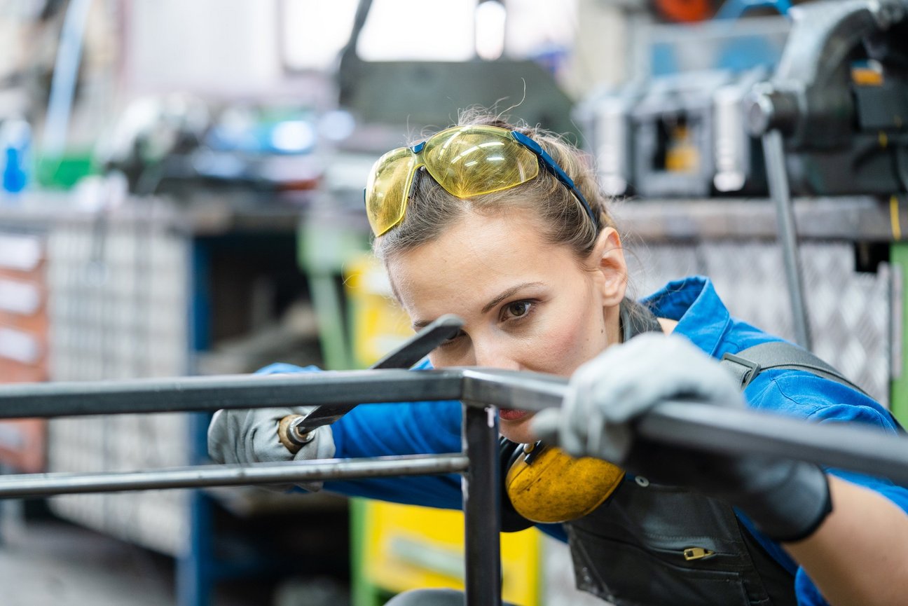 Eine Frau arbeitet mit Metallstangen.