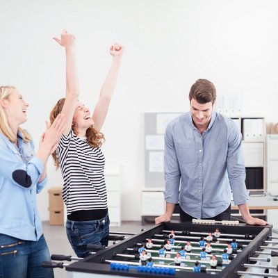 Eine Gruppe von Personen spielt Tischfußball im Büro