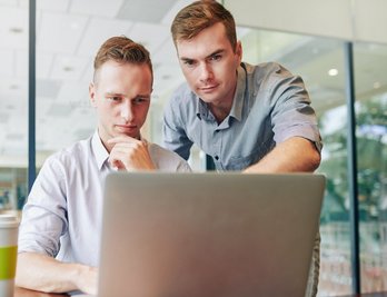 Zwei Männer betrachten einen Laptop-Computer.