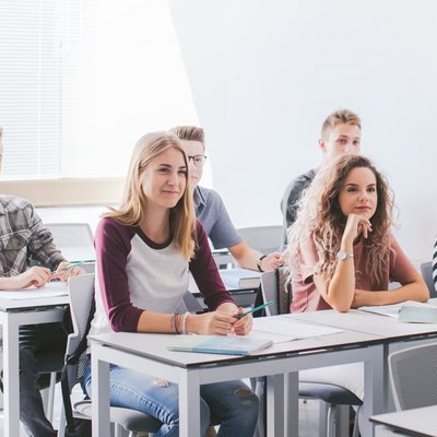 Eine Gruppe von Schülern sitzt an Tischen in einem Klassenzimmer.