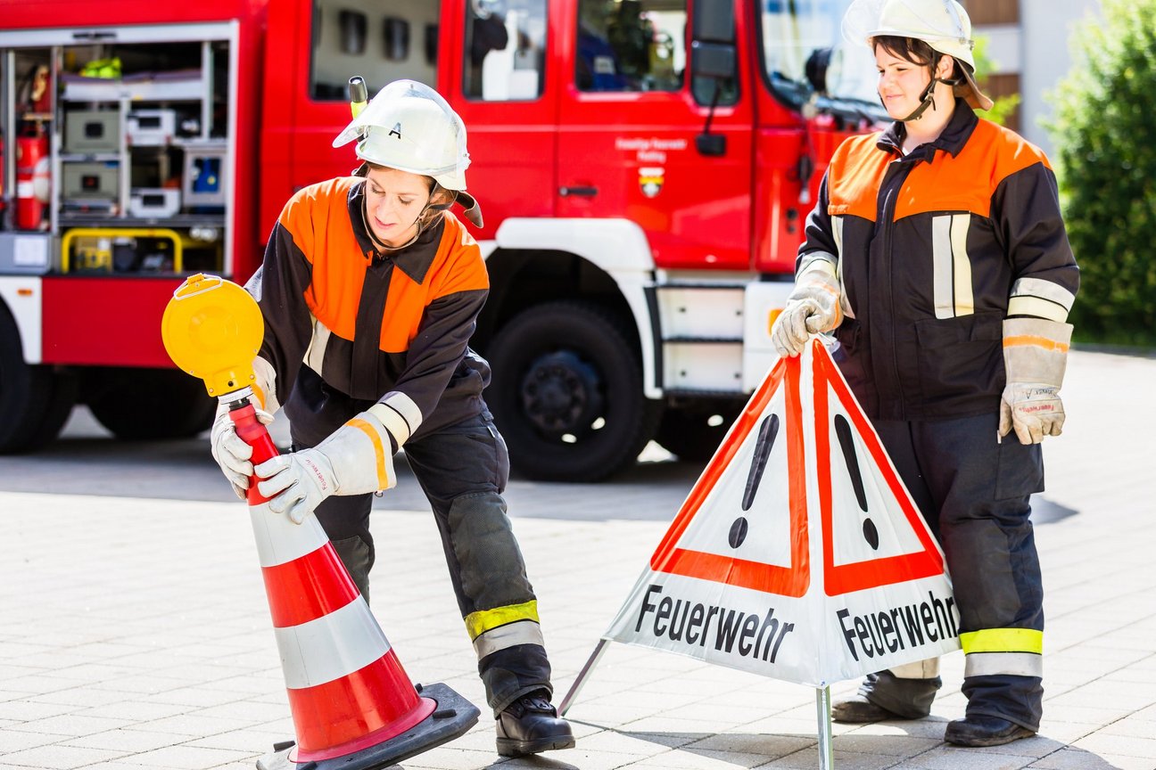 Zwei Personen in Feuerwehr Kleidung tragen Schilder