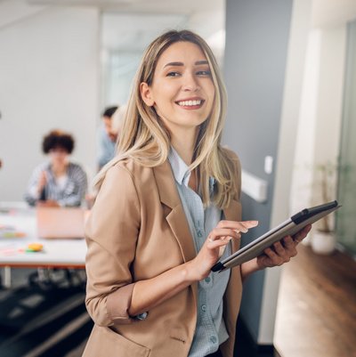 Eine Frau in einem Business-Anzug hält ein Tablet.