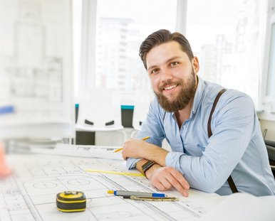 ein lachender Mann sitzt am Schreibtisch