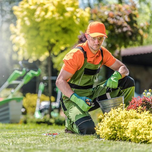 Ein Mann in Arbeitsuniform arbeitet im Garten.