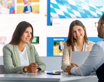 Zwei Frauen unterhalten sich mit einem Mann im Büro.