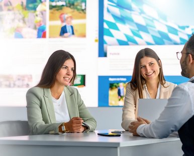 Zwei Frauen unterhalten sich mit einem Mann im Büro.