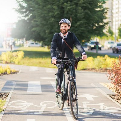 Ein Mann in einem Anzug fährt mit dem Fahrrad auf einer Straße.