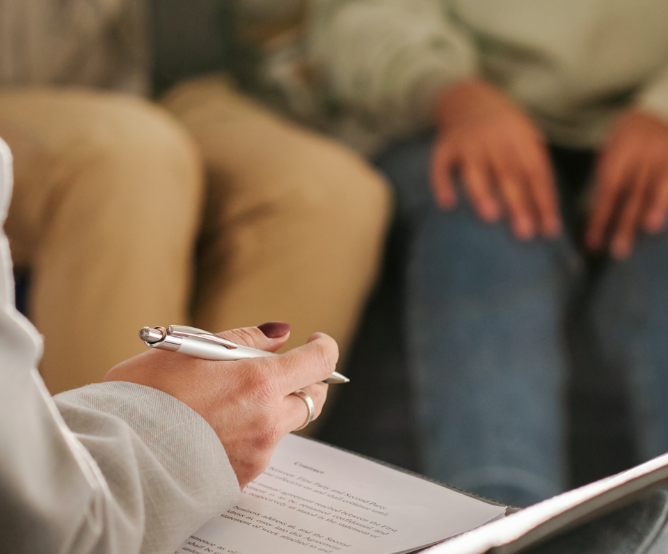 Eine Person sitzt auf einem Sofa mit einem Stift und Papier.