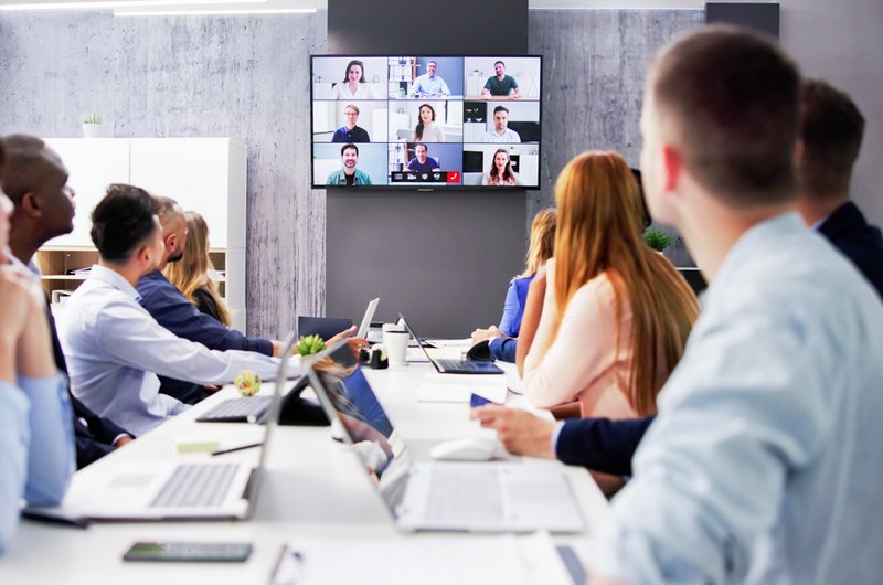 Eine Gruppe von Personen sitzen in einem Büro und schauen auf den Fernseher.