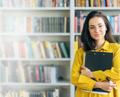 Frau in gelber Bluse vor einem Bücherregal