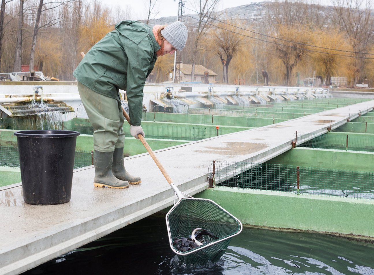 Ein Mann mit einem Fischernetz am Wasser.