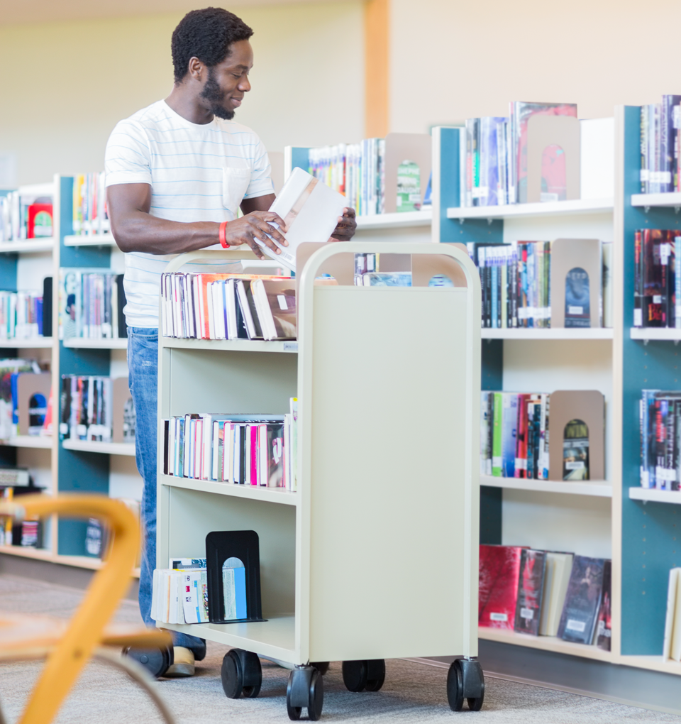 Ein Mann räumt in einer Bibliothek die Bücher in die Regale ein.