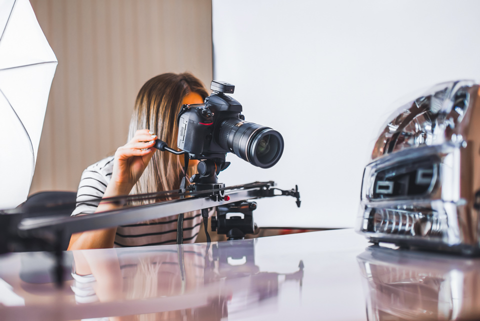 Eine Frau fotografiert mit einer Spiegelreflexkamera ein Produkt.