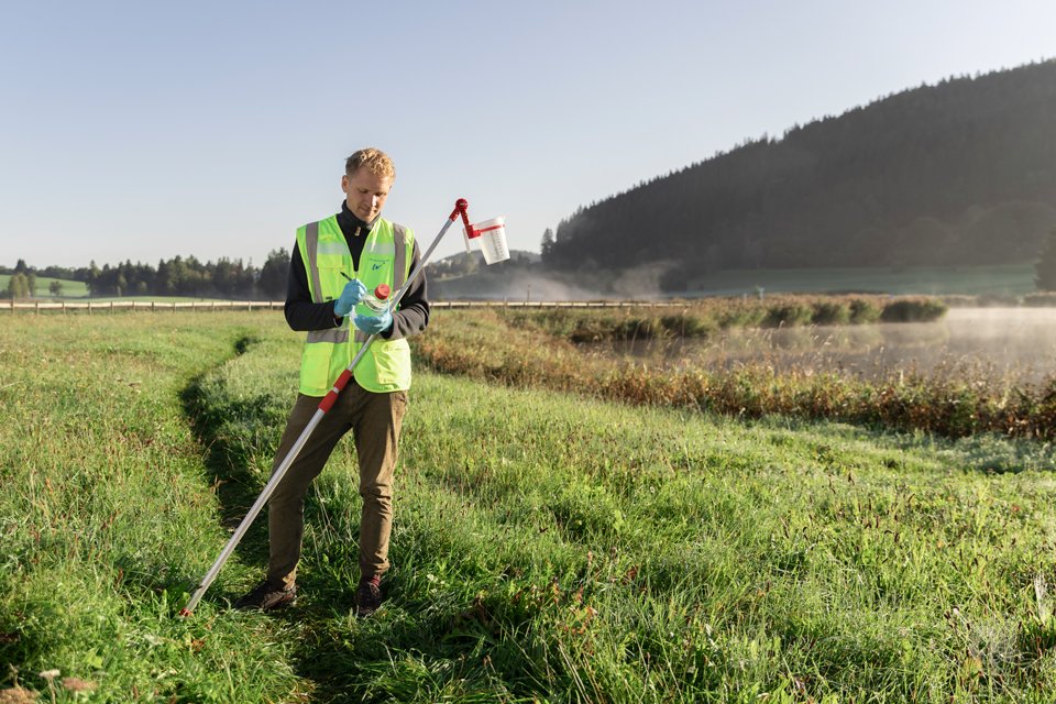 Ein Mann mit Sicherheitsweste steht auf einem Feld.