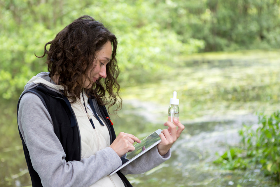 Eine Frau steht vor einem Fluss und schreibt etwas auf.