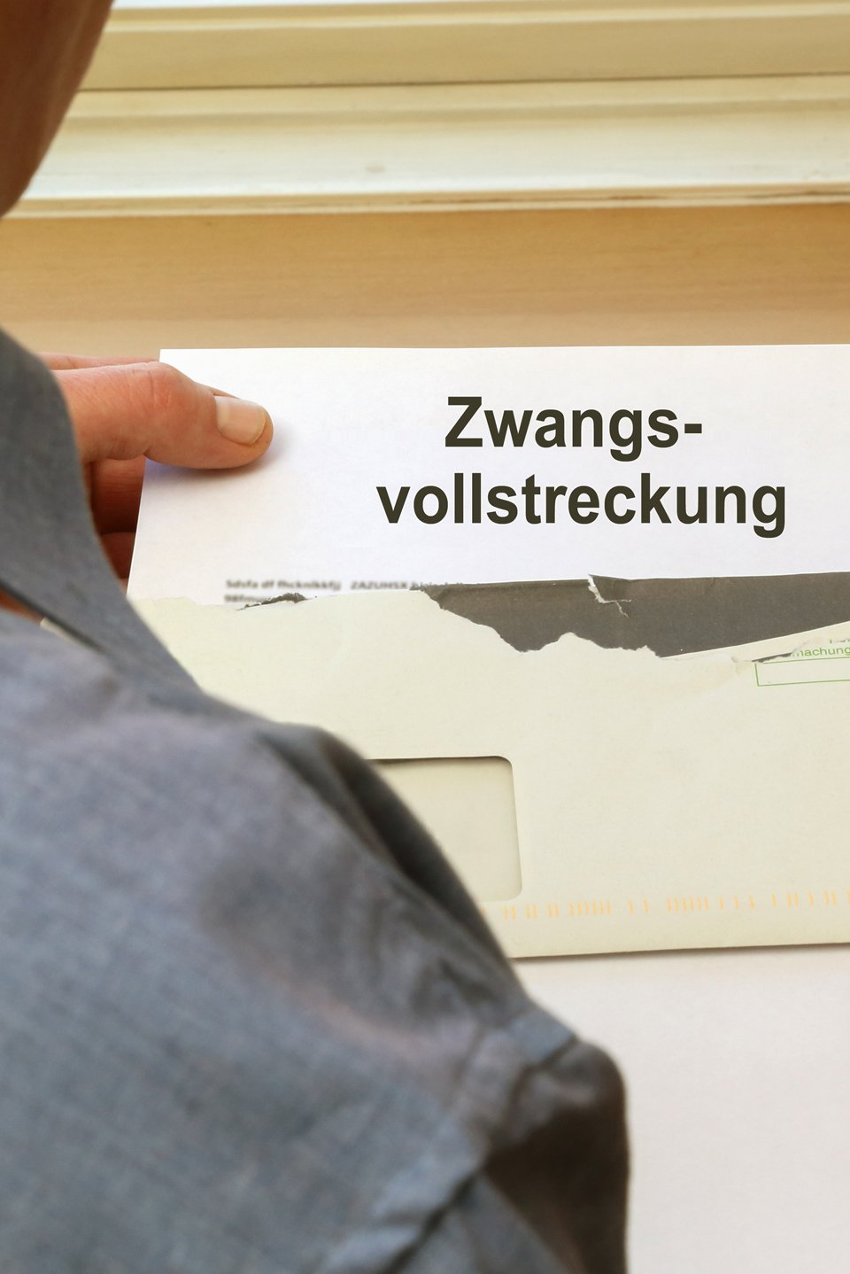 Eien Person öffnet einen Brief mit einer Zwangsvollstreckung.