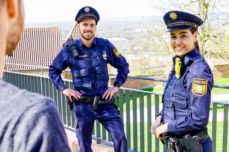 Eine Polizistin und ein Polizist unterhalten sich mit einer dritten Person.