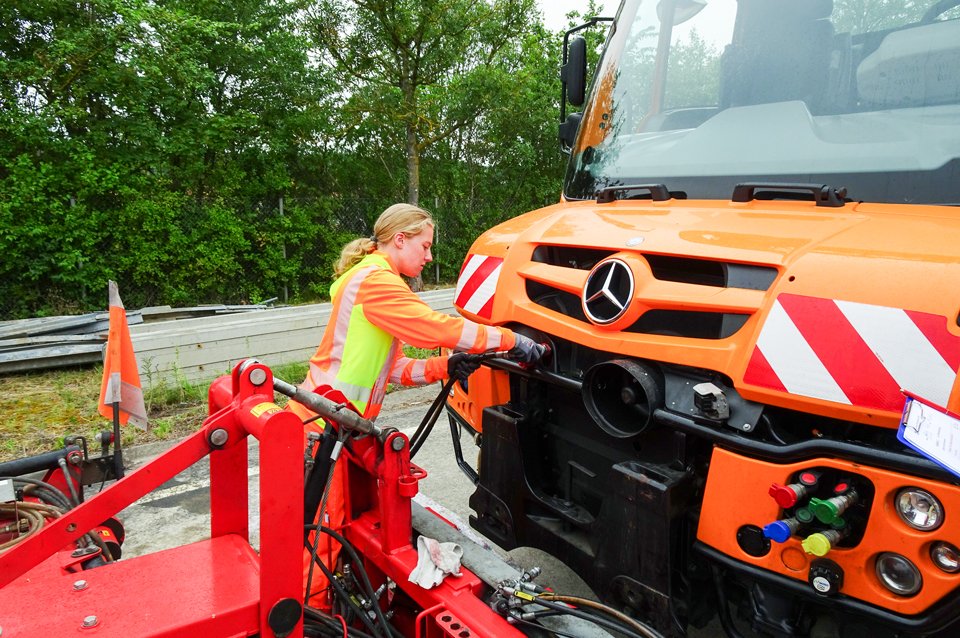 Eine Frau steht vor einem Baustellenfahrzeug.