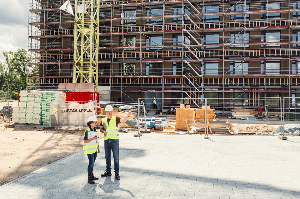 Zwei Personen stehen vor einem Gebäude, welches grade gebaut wird.