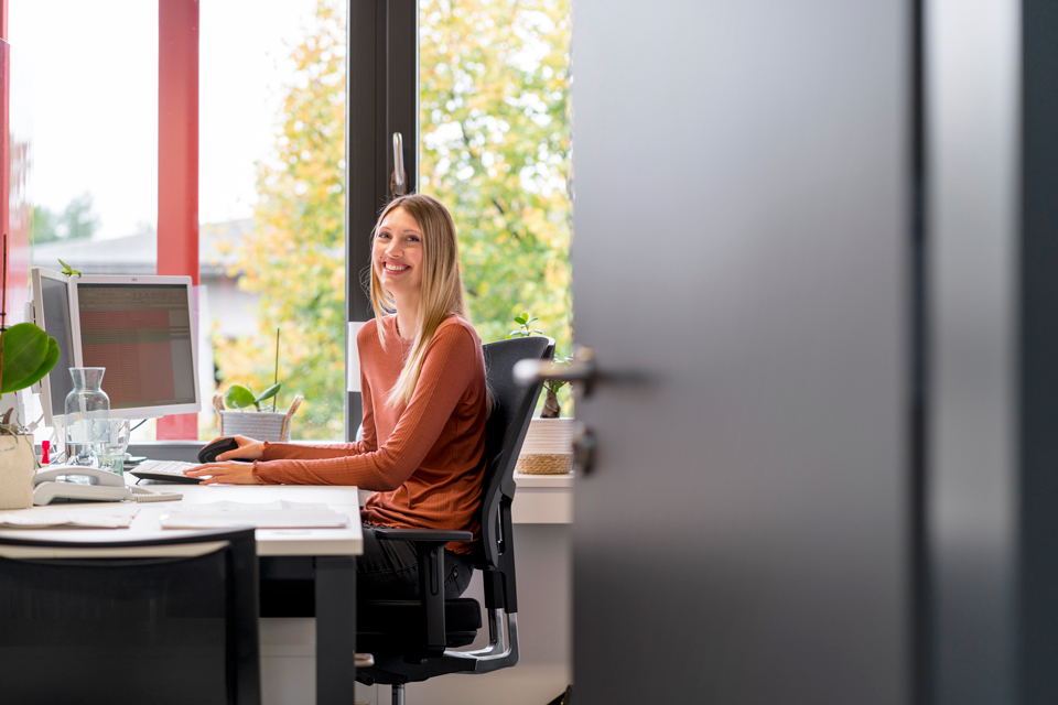 Eine lachende Frau sitzt in ihrem Büro