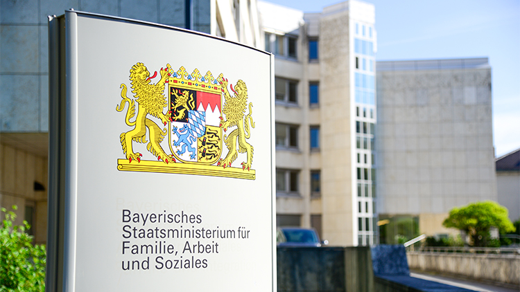 Schild für das Bayerische Staatsministerium für Familie, Arbeit und Soziales im Vordergrund des Gebäudes.